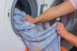 Une personne sort un drap de la machine à laver